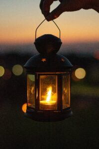 Person holding a glowing lantern at dusk.